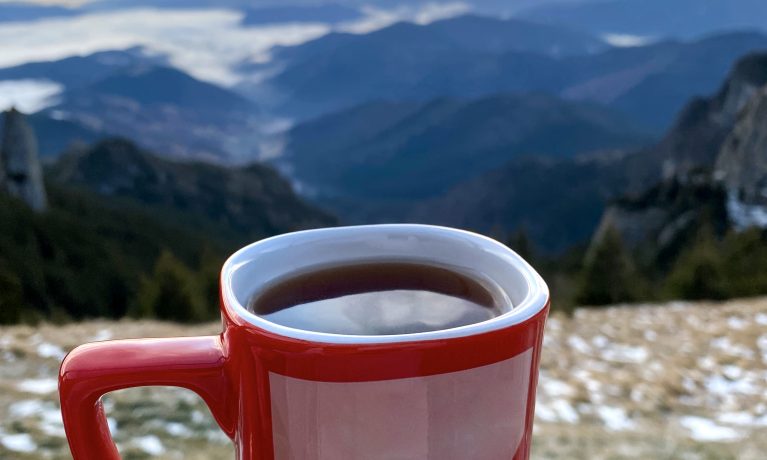A cup of coffee on the Toaca peak in the Carpathians at sunset, Romania